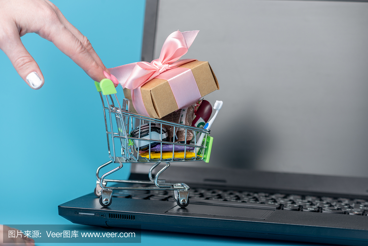 将日常购买的物品放在购物车上,键盘上以蓝色为背景。网上购物